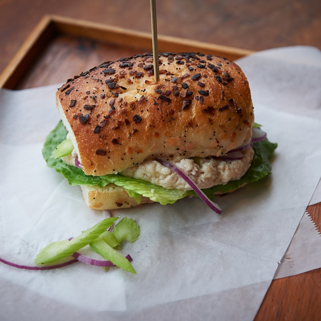 Whitefish salad sandwich with red onion, celery on an onion roll
